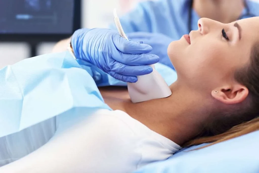 A medical professional performing a thyroid ultrasound on a female patient at a specialized endocrinology clinic.