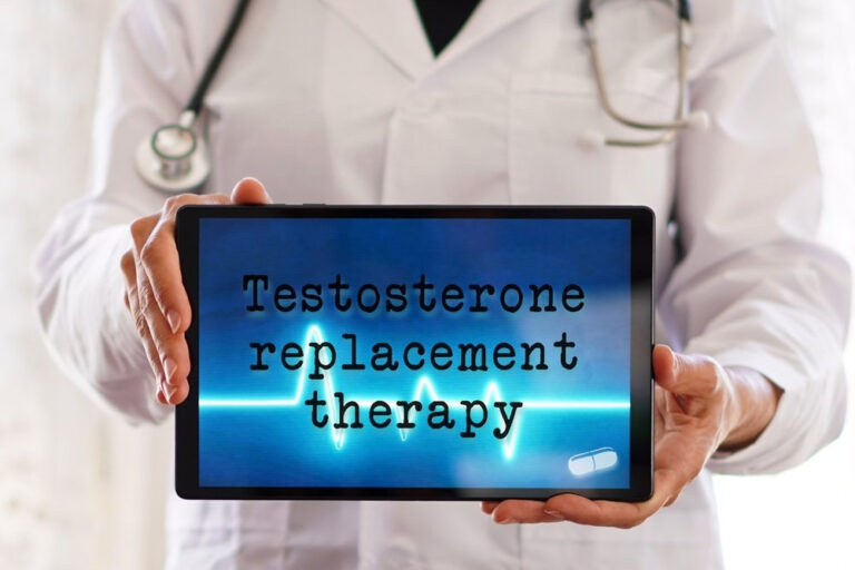 A medical professional in a white coat holding a tablet that displays the text 'Testosterone replacement therapy' over a blue pulse wave graphic.